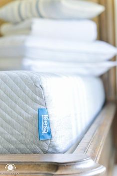 there is a mattress with a tag on it in front of some pillows and blankets