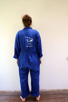 "Vintage blue chore coveralls from Israeli flight school printed in Hebrew on the back and front...\" Amal Ramat David Building the future\" with an F16 airplane drawing on the back panel, pockets with velcro opening, zips down the front, elastic waist on the back, soft cotton. an oversize and loose fit can be worn by both men and women. aside from minor signs of wear...The back hem of the pants is worn, otherwise, good vintage condition clean ready to wear. **Model is 5'8\" and a size s/m for r Blue Cotton Long Sleeve Denim Jumpsuit, Blue Cotton Denim Jumpsuit With Long Sleeves, Blue Long Sleeve Cotton Denim Jumpsuit, Vintage Blue Cotton Shortalls, Vintage Blue Cotton Overalls, Blue Vintage Cotton Shortalls, Vintage Blue Long Sleeve Overalls, Blue Utility Jumpsuits And Rompers With Relaxed Fit, Vintage Cotton Jumpsuits And Rompers In Relaxed Fit