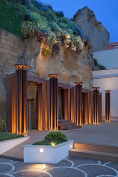 an outdoor area with steps and planters lit up at night, next to a stone wall