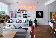 a living room filled with lots of furniture next to a white brick wall covered in pictures