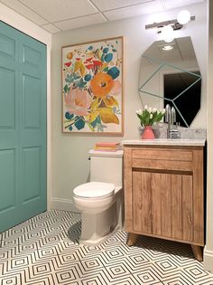 a bathroom with a blue door and white toilet next to a wooden cabinet in front of a mirror