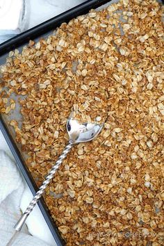 granola in a baking pan with a spoon on the side, ready to be eaten