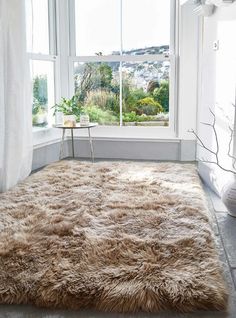 a large shaggy rug in front of a window with white curtains and windowsills