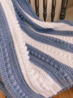 a blue and white crocheted blanket sitting on top of a wooden stair case