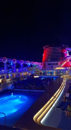 an empty pool on the deck of a cruise ship at night with people sitting in chairs