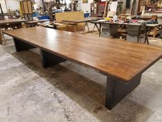 a large wooden table in a shop surrounded by other tables and workbench's