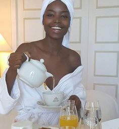 a woman in a towel is pouring orange juice into a teapot