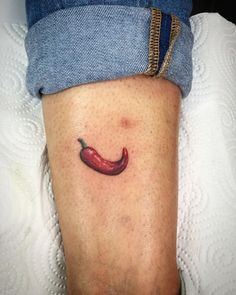 a red chili pepper tattoo on the leg