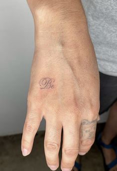 a person's hand with a small tattoo on their left wrist and the word b is in cursive writing