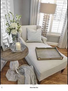 a living room filled with furniture and flowers on top of a coffee table in front of a window