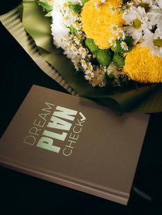 a bouquet of flowers sitting on top of a book next to it's cover