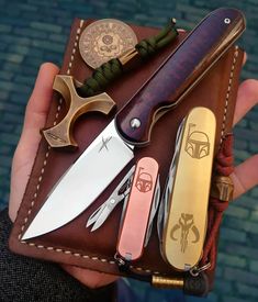 a person holding a wallet with several different types of knives in it