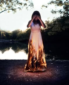 a woman standing in front of a fire with her hands on her face