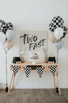 a table topped with balloons and cake next to a sign that says, two fast