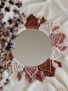 a round mirror sitting on top of a table next to a vase filled with flowers