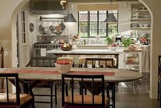 a kitchen with an archway leading into the dining room and kitchen area, along with a table set for four