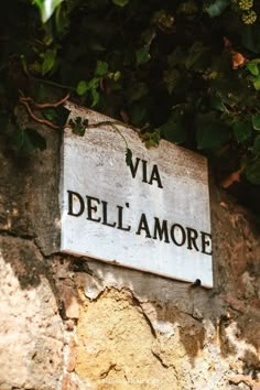 a sign that is on the side of a stone wall with ivy growing over it