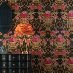 an ornate wallpaper with pink flowers on it and a black dresser next to it