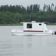 a white boat traveling down a river next to a forest