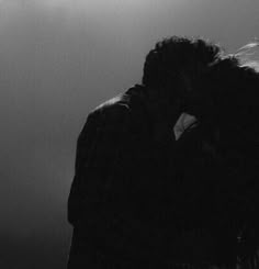 two people are kissing in the dark with their arms around each other and one person is holding his head