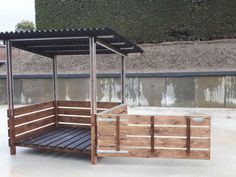 a wooden cart with a canopy attached to the top and bottom part, in front of a stone wall