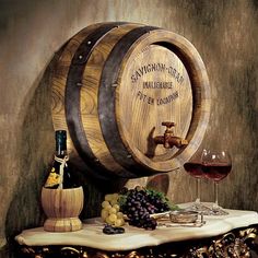 two wooden barrels with wine glasses on a table next to grapes and cheese, along with a bottle of wine