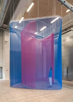 a person standing in front of a blue and pink structure