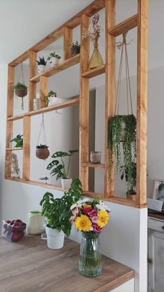 a vase filled with flowers sitting on top of a wooden table next to a mirror