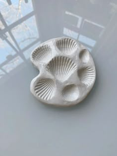 a white ceramic dish with four shells on the bottom and one shell in the middle