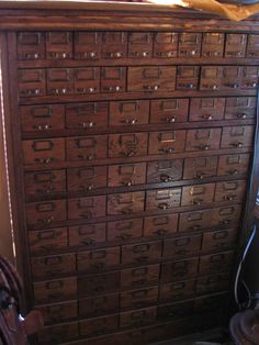 an old wooden dresser with lots of drawers on top of it and a cat laying on the floor next to it