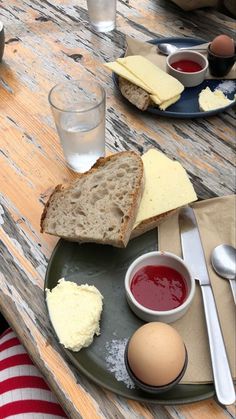 a plate with bread, butter and eggs on it next to some glasses of water