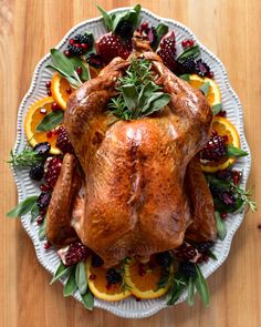 a roasted turkey on a platter with oranges and berries