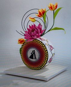 a vase with flowers in it sitting on top of a white table next to a wall