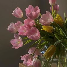 a vase filled with pink and yellow tulips on top of a wooden table