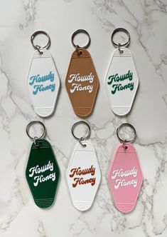 six keychains with different colors and designs on them sitting on a marble surface