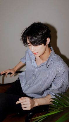 a young man sitting on top of a wooden table holding a remote control in his hand