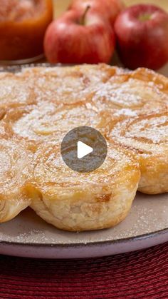 an apple pie on a plate with apples in the background