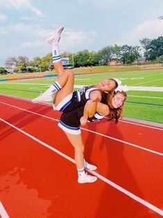 two cheerleaders are posing for a photo on the track