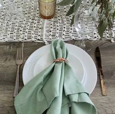 a place setting with green napkins and silverware