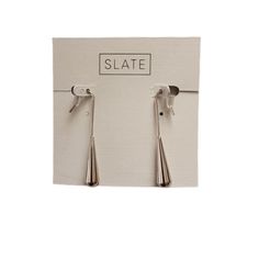 two silver spoons hanging from the side of a white sign that says slate on it