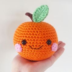 a crocheted orange with a green leaf on it's head and eyes