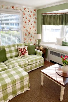 a living room with green and white checkered couches, coffee table, window curtains and flowers on the windowsill