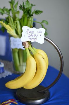 three bananas on a stand with a sign attached to them