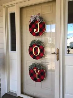 two christmas wreaths hanging on the front door of a house with joy written on them