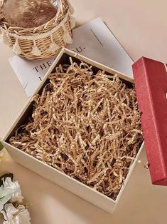 an open box with wood shavings in it on a table next to flowers