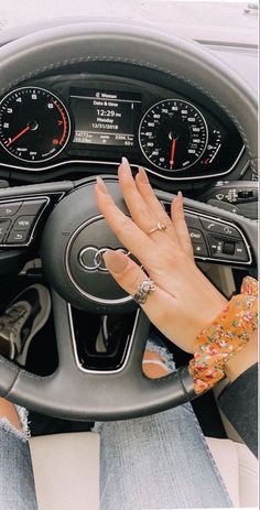 a woman is sitting in the driver's seat of a car with her hands on the steering wheel