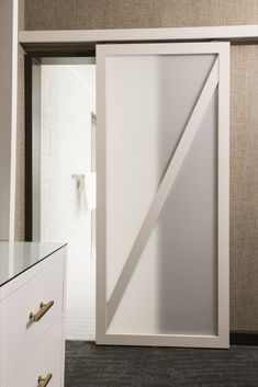 an open sliding door in a bathroom next to a white dresser and mirror with gold handles