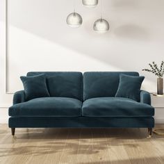 a blue couch sitting on top of a hard wood floor next to a white wall