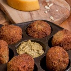 a muffin tin filled with different types of food next to a knife and butter