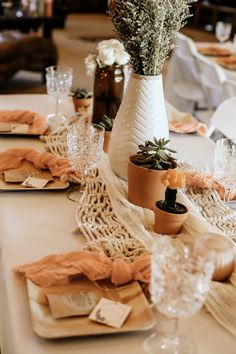 the table is set with place settings and flowers in vases on top of napkins